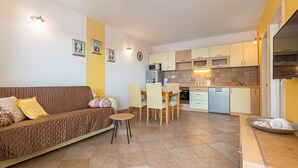 A compact living space with a sofa, dining table, chairs, and a kitchenette. - Villa Anima in Makarska, private pool (Makarska)