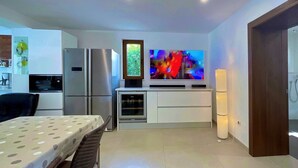 Una cocina moderna con horno empotrado, refrigerador y televisor de pantalla plana colocado sobre el horno.