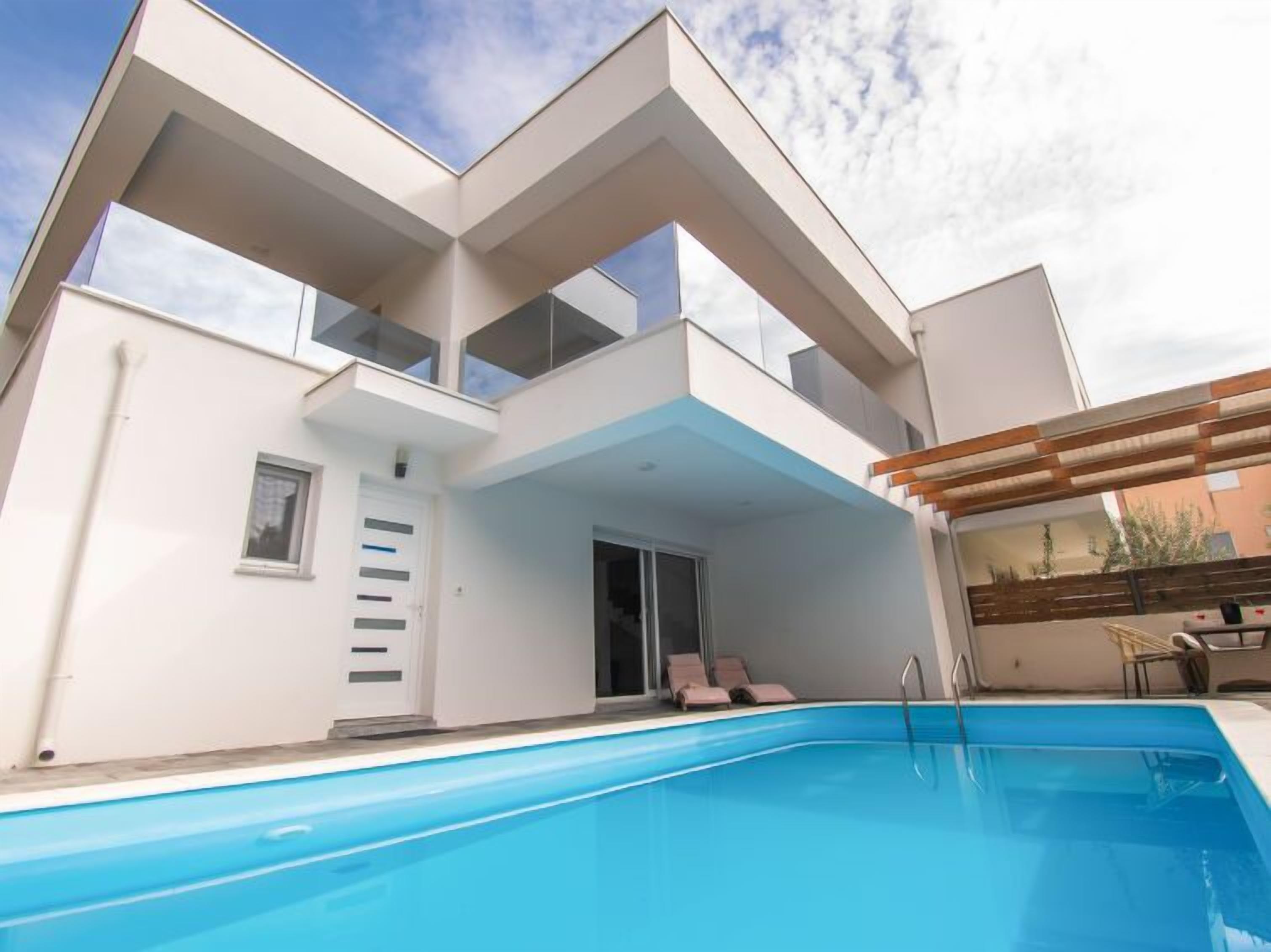 A modern two-story building with a swimming pool in the foreground.