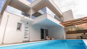 A modern two-story building with a swimming pool in the foreground.
