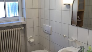 A bathroom with a toilet, sink, and window. - Neveu Josephsberg Winery (Durbach)