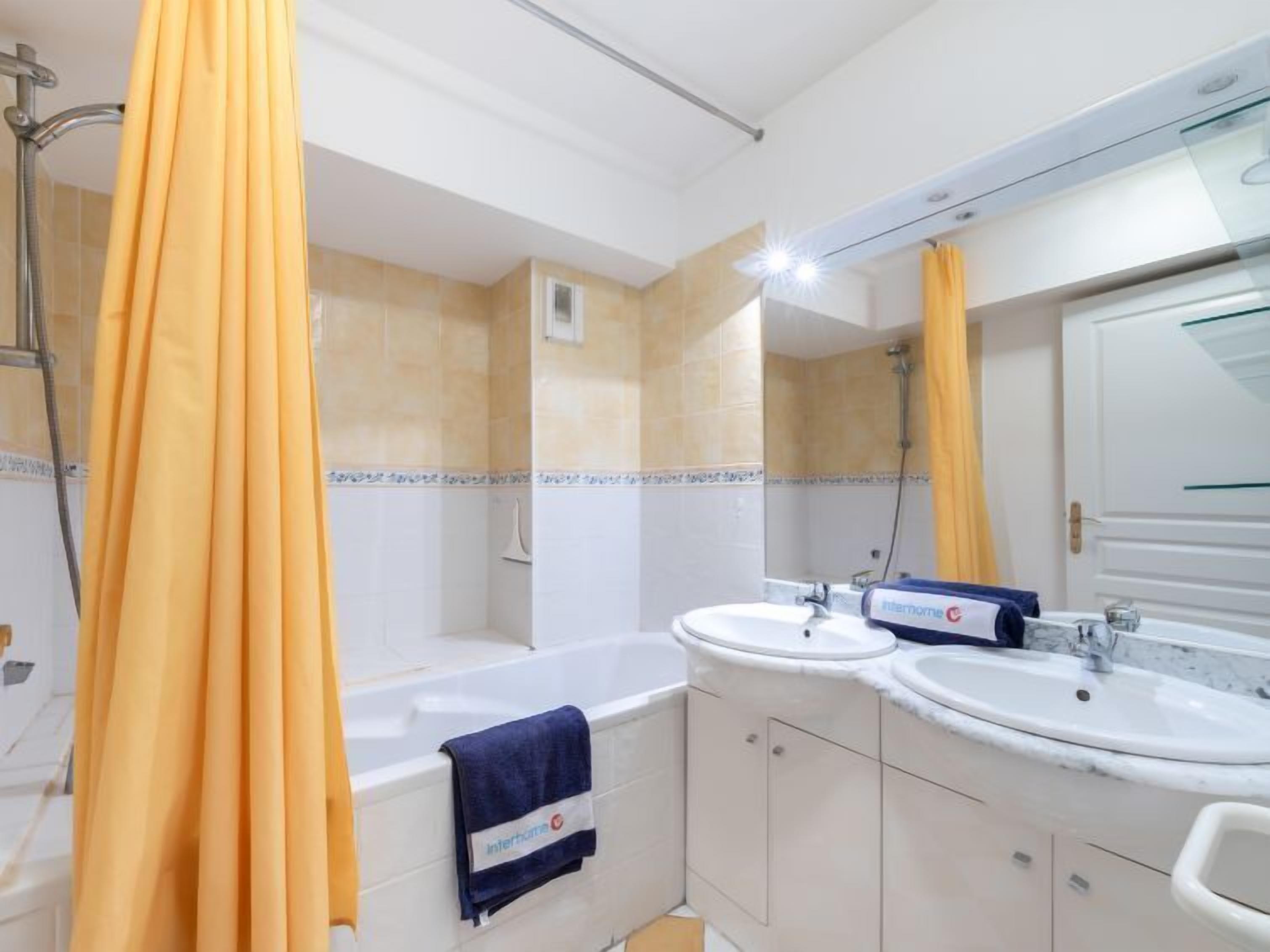 Une salle de bain avec une baignoire, deux lavabos et une douche.