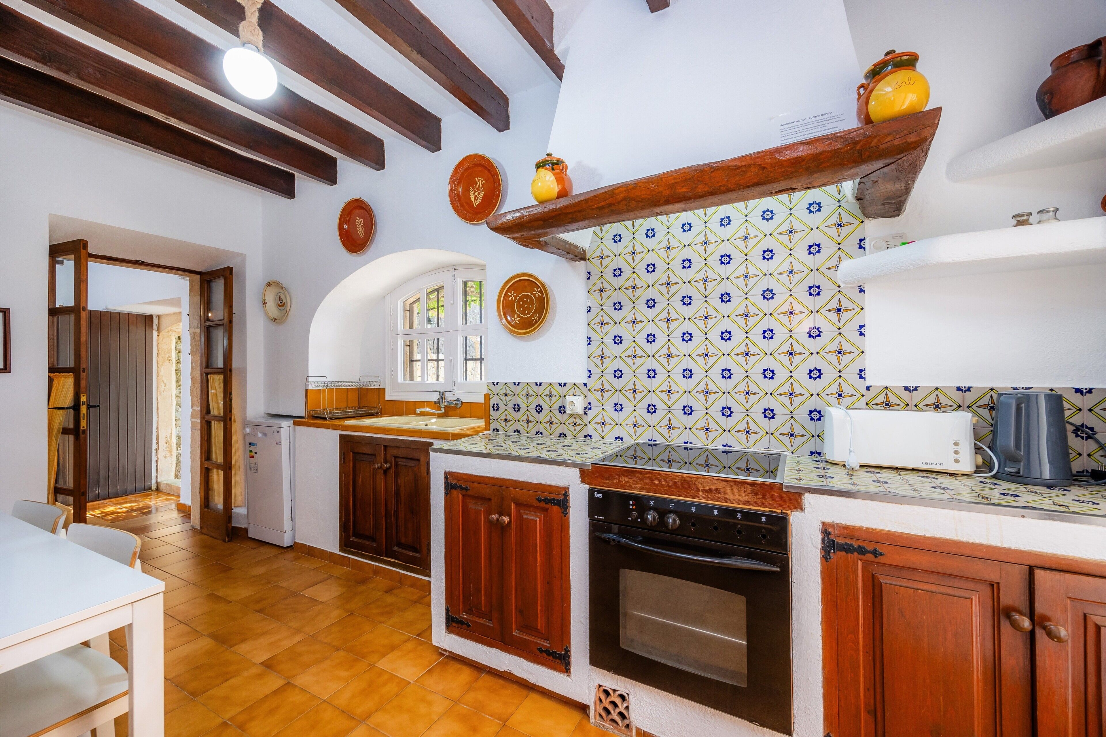 Una cocina con armarios de madera, encimera blanca, estufa y tostadora.