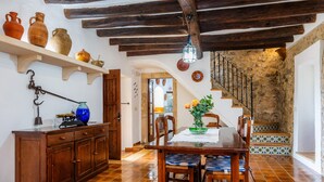 Un comedor rústico con mobiliario de madera, piso de baldosas y pared de piedra.