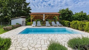 Ein Swimmingpool mit Liegestühlen und einer Pergola unter blauem Himmel.