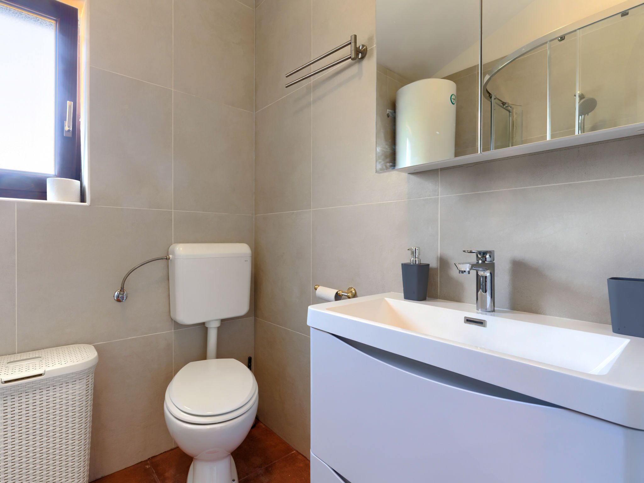 A modern bathroom with a toilet, sink, and a mirror above the sink.