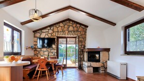Ein gemütliches Interieur mit Kamin aus Stein, Holzmöbeln und einem an der Wand befestigten Fernseher.