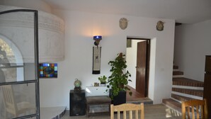 Een kamer met een houten stoel, een klein tafeltje, een potplant, een wereldbol en een wandlamp.