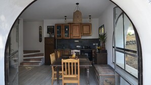 Een keuken met houten kasten, een eettafel met stoelen en een hanglamp.