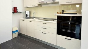 A modern kitchen with a black oven, a coffee maker, and a sink. - Molo Lozna by Interhome (Brač/Postira)