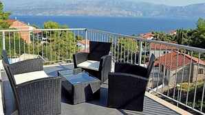 A balcony with wicker furniture overlooking a coastal view. - Molo Lozna by Interhome (Brač/Postira)
