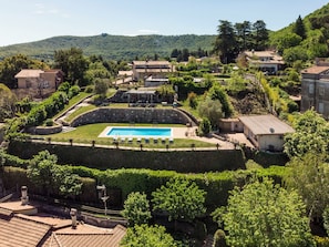 A pool surrounded by stone walls, with a view of a hillside and residential buildings.