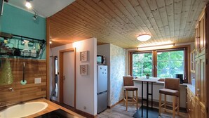 Een moderne keuken met houten plafond, een inbouwfornuis, een koelkast en een eethoek met stoelen en een tafel.