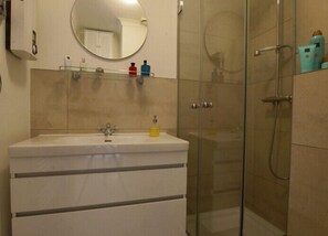 Ein Badezimmer mit Waschbecken, Spiegel und Duschkabine.