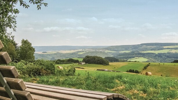 Eine Bank mit Blick auf eine ländliche Landschaft mit sanften Hügeln und Feldern.