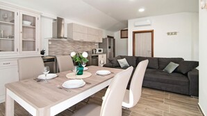 Une cuisine moderne avec un coin repas, comprenant une table mise pour deux personnes, avec assiettes, verres et un vase de fleurs.