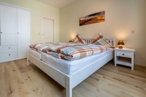 A bedroom with a bed, a nightstand, a wardrobe, and a painting on the wall. - Vacation apartment Kruggel 2 (Zinnowitz)