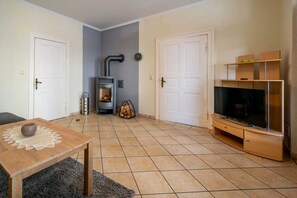A living room with a fireplace, a TV, and a wooden TV stand. - Vacation apartment Kruggel 2 (Zinnowitz)