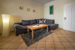 A living room with a grey sofa, a wooden coffee table, a grey rug, and a white door. - Vacation apartment Kruggel 2 (Zinnowitz)