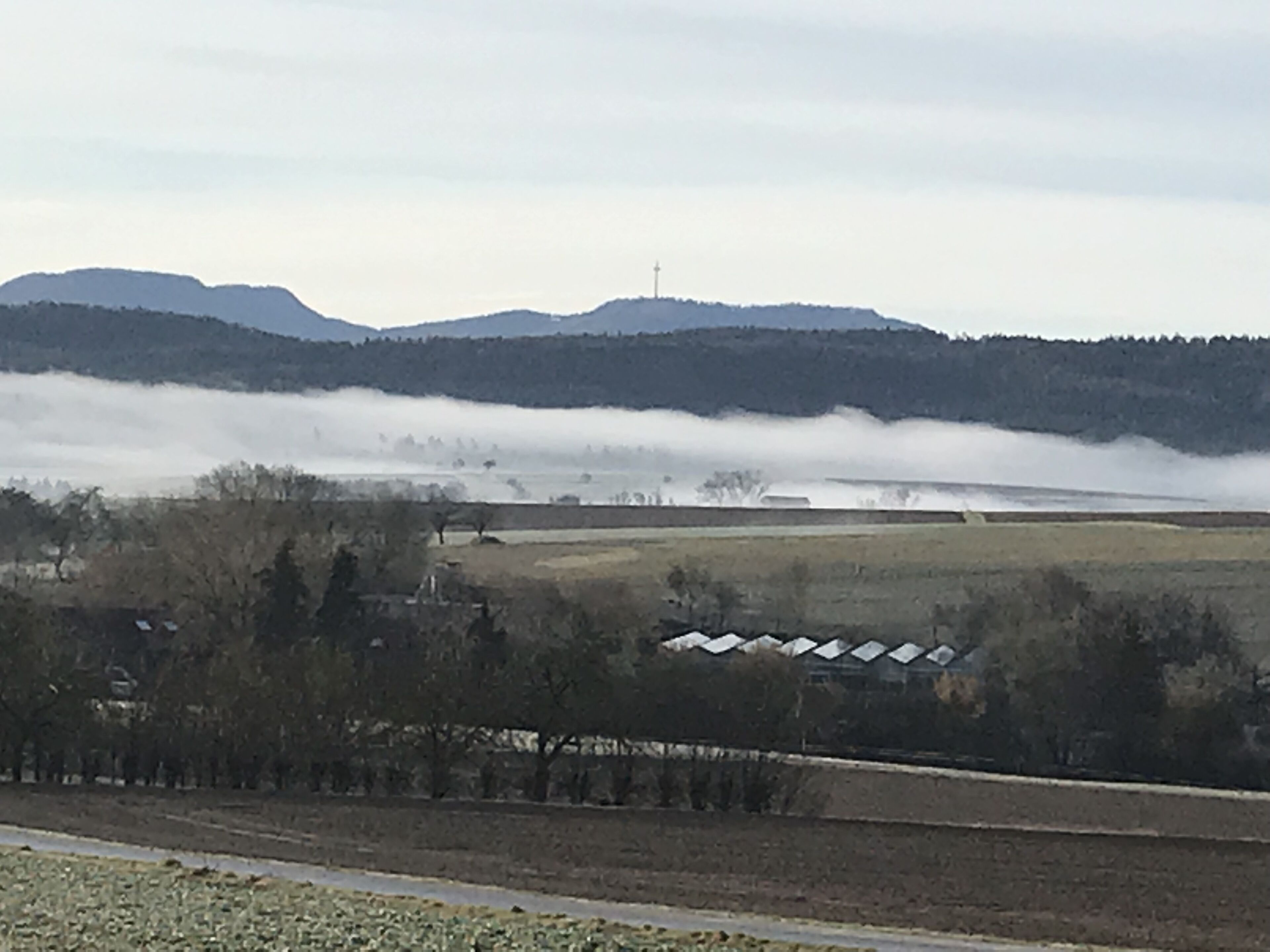 Ländliche Landschaft mit einer Straße, Feldern und einem fernen Gebirge.