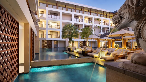 A hotel with a swimming pool, outdoor seating, and a decorative lion head sculpture. - Royal Suites at The Bandha (Legian)