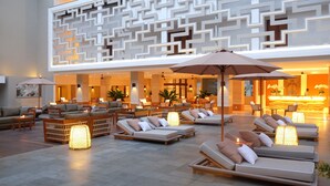 A spacious lobby with multiple seating areas, including sofas and lounge chairs, and a reception desk in the background. - Royal Suites at The Bandha (Legian)