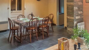 Een eetgedeelte met een tafel gedekt voor zes personen, omringd door zes stoelen. Een klok hangt aan de muur boven de tafel.