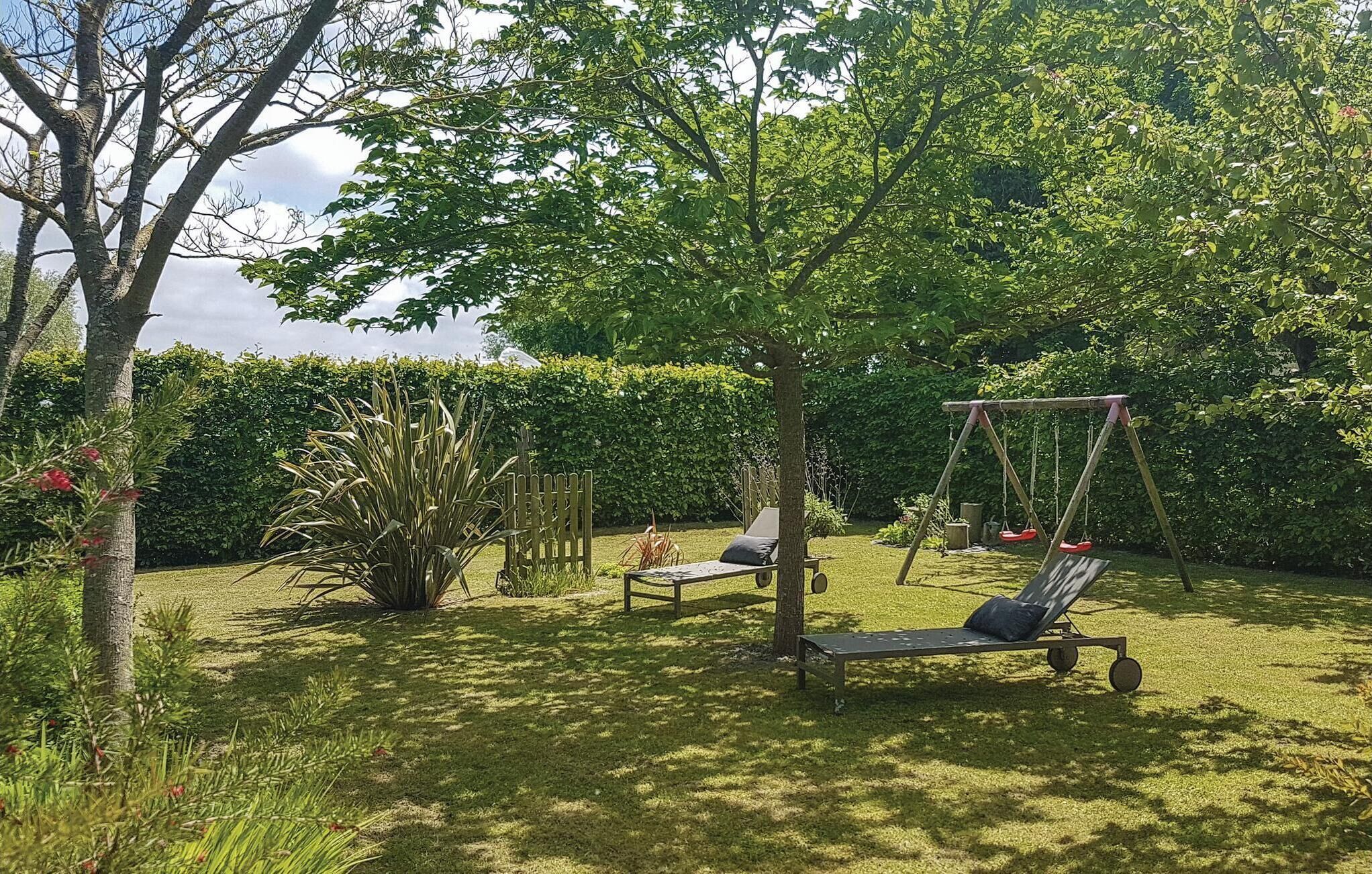 Ein Garten mit Schaukel, zwei Liegestühlen und einem kleinen Tisch.