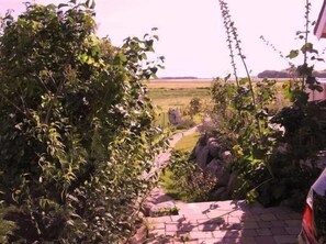 Stroll along the beautifully maintained garden pathway to a serene grassy field.
