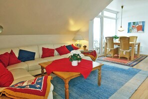 A living room with a sofa, a coffee table, a dining table with chairs, a lamp, and a painting on the wall.