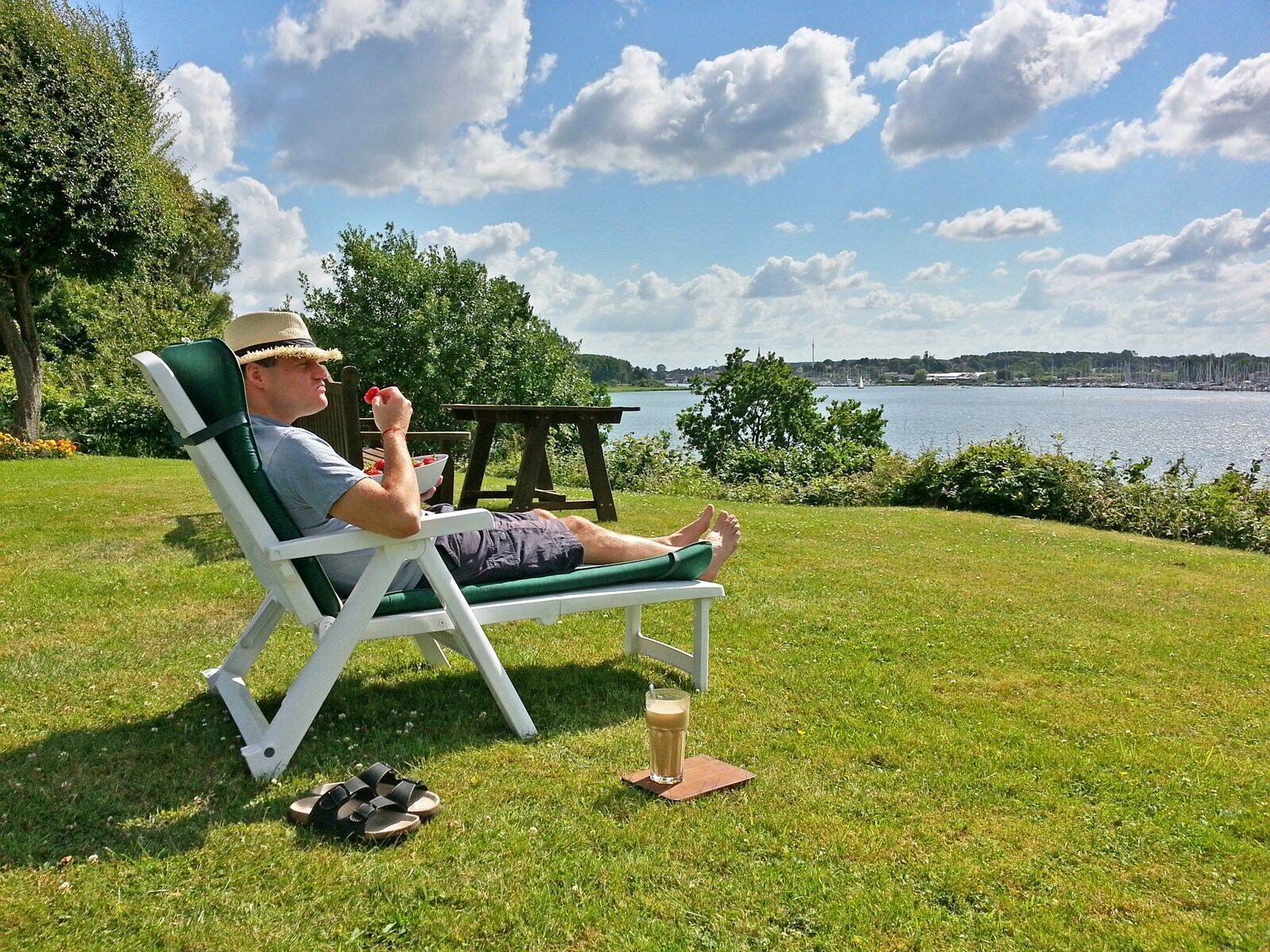 A person relaxing on a lawn chair with a view of a lake and city skyline.
