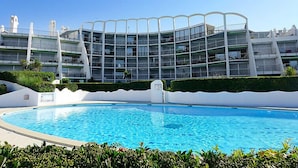 Un hotel moderno con piscina, que destaca por una fachada curva distintiva y múltiples balcones.