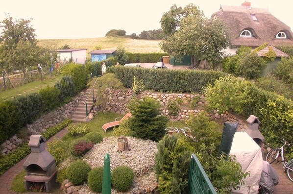 Escape to a serene garden oasis with a rustic seating area and thatched-roof building.