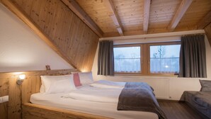 Una habitación con paneles de madera, una cama, un ventanal con cortinas y un radiador.