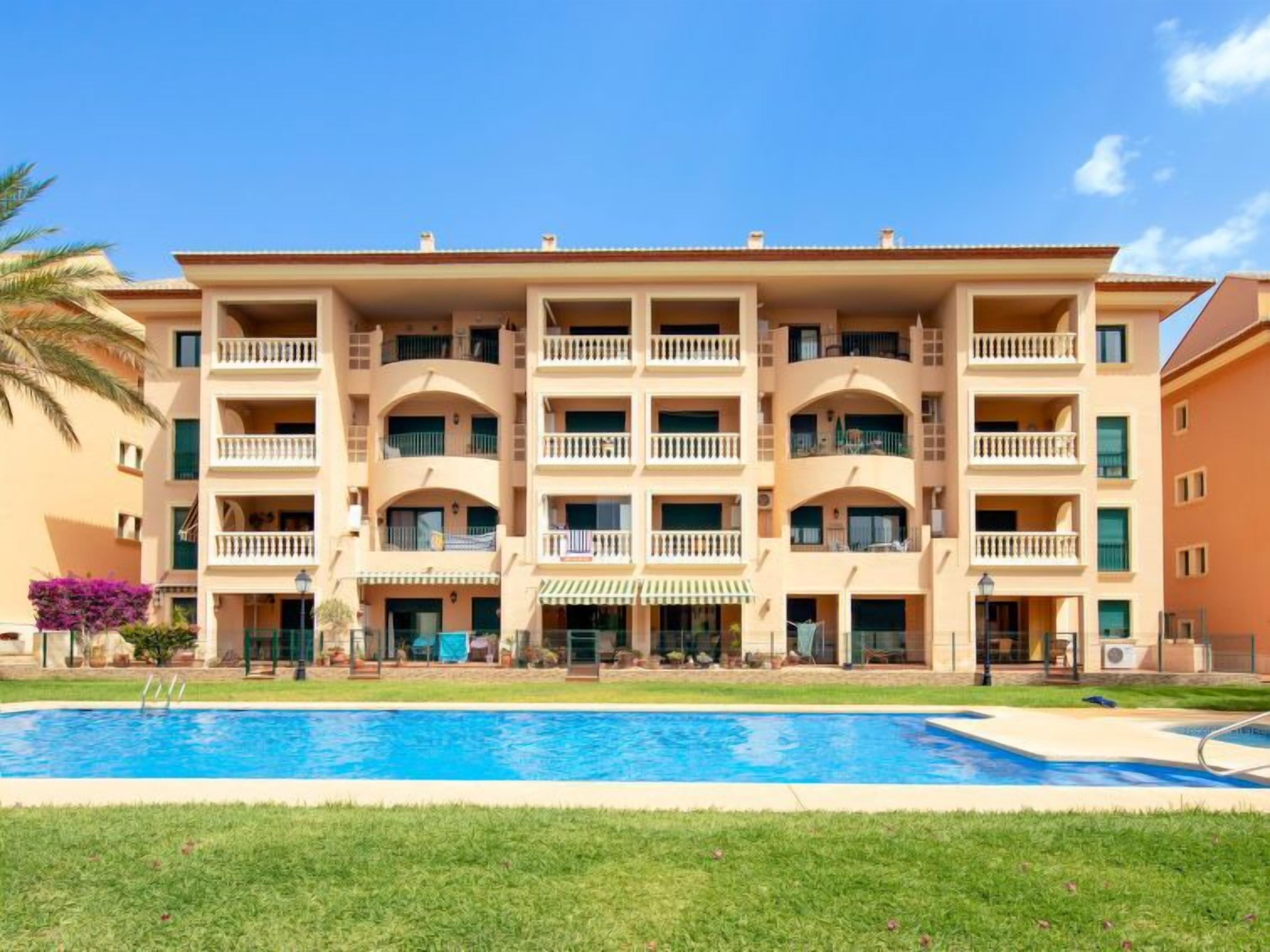 A multi-story hotel with a swimming pool in front.