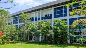 A modern building with a large glass facade, surrounded by lush greenery and trees. - Senggigi Homes & Apartments (Senggigi)