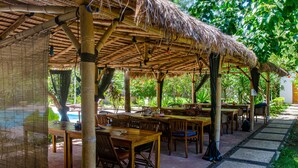 An outdoor dining area with bamboo structures and tables. - Senggigi Homes & Apartments (Senggigi)