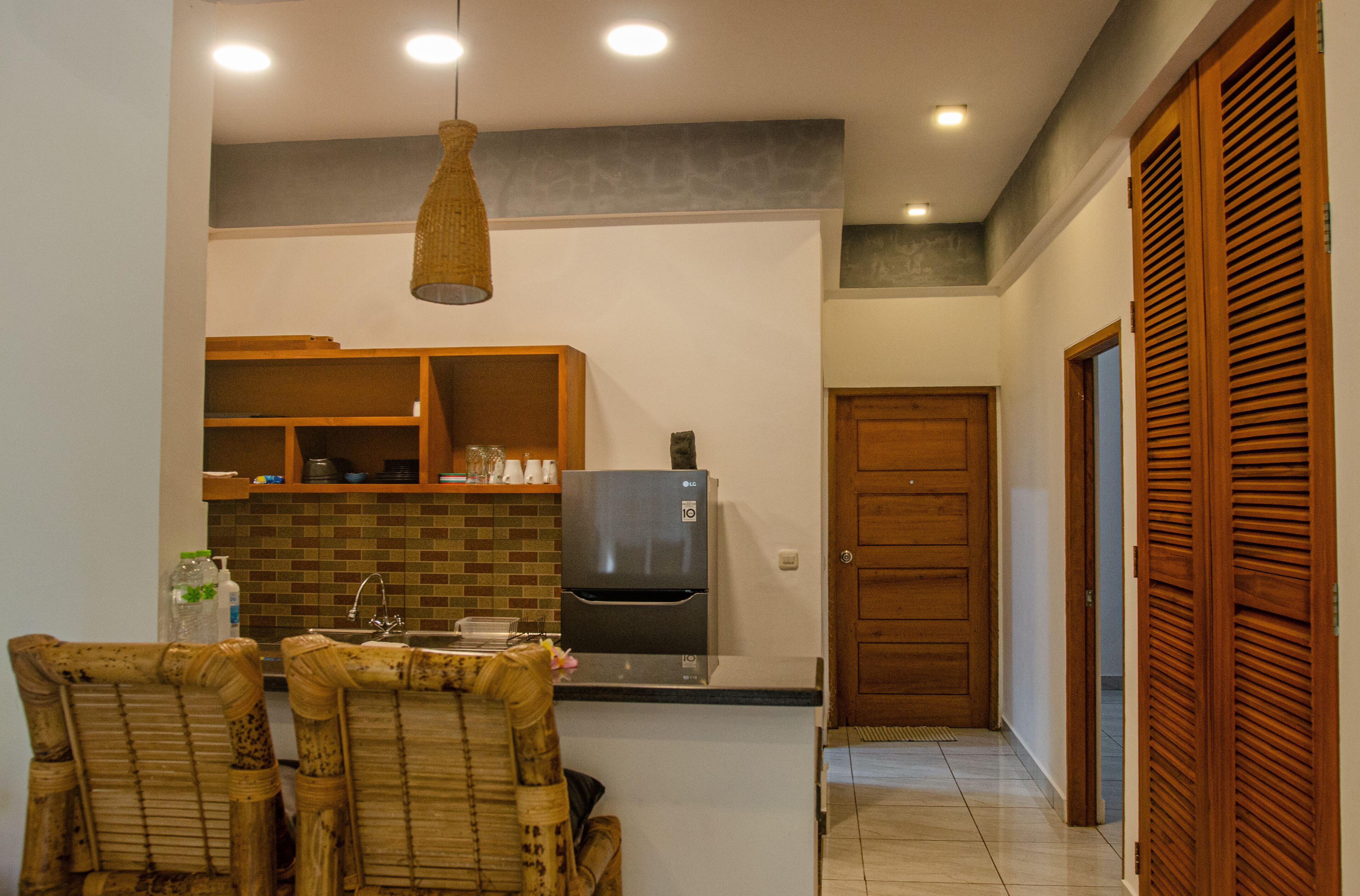 A kitchen with a refrigerator, wooden cabinets, and a dining area with chairs.