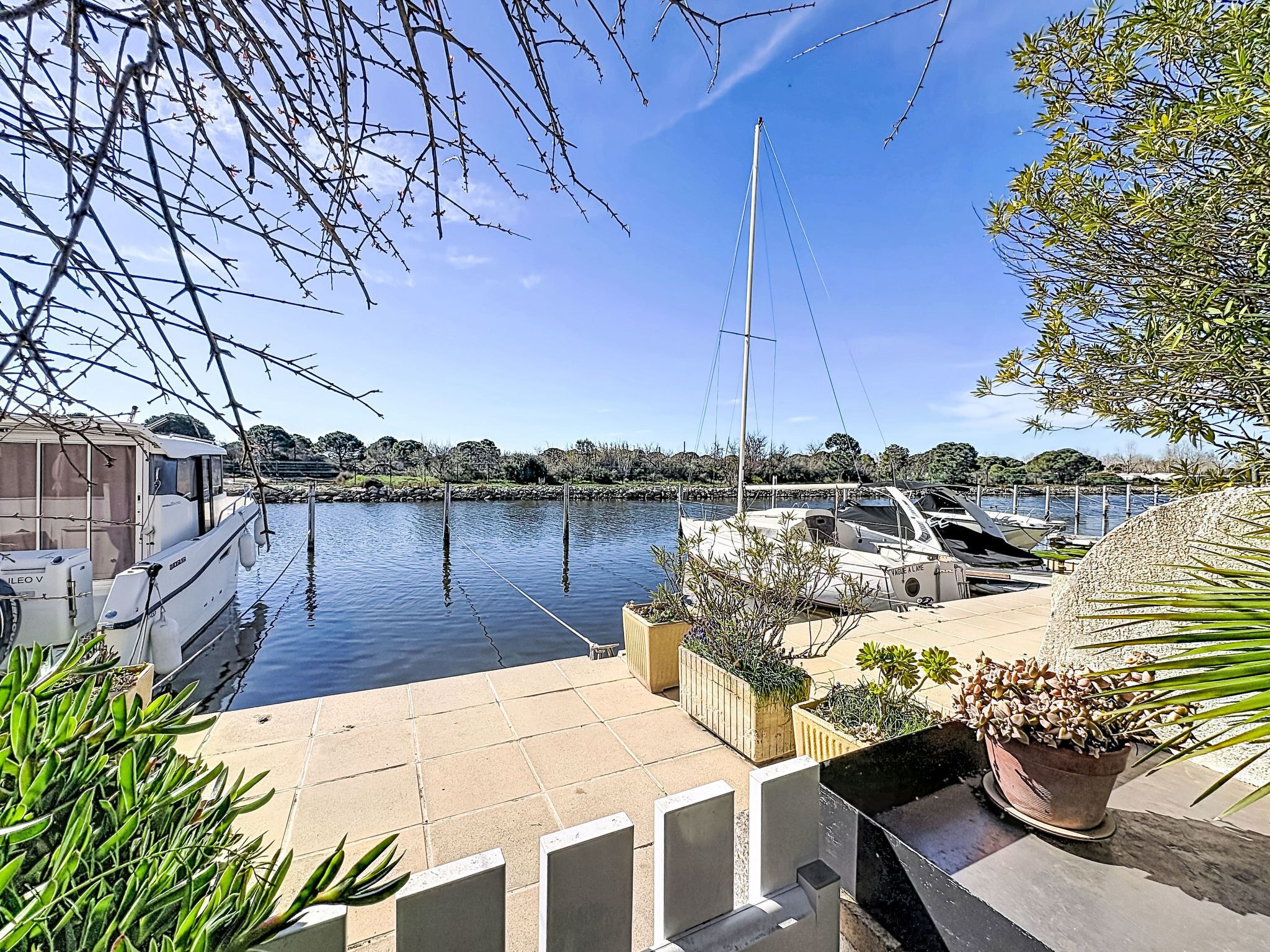 A marina with boats docked, a clear sky, and a calm water body.