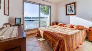 Una camera da letto con un letto grande, una scrivania con un computer, una sedia, un quadro appeso al muro e vista attraverso una porta scorrevole.