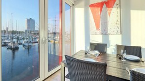 Een eetruimte met uitzicht op een jachthaven en een hoog gebouw op de achtergrond.