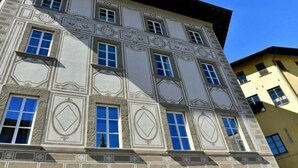 Un edificio de varios pisos con detalles arquitectónicos ornamentales, incluyendo molduras decorativas y una fachada simétrica.