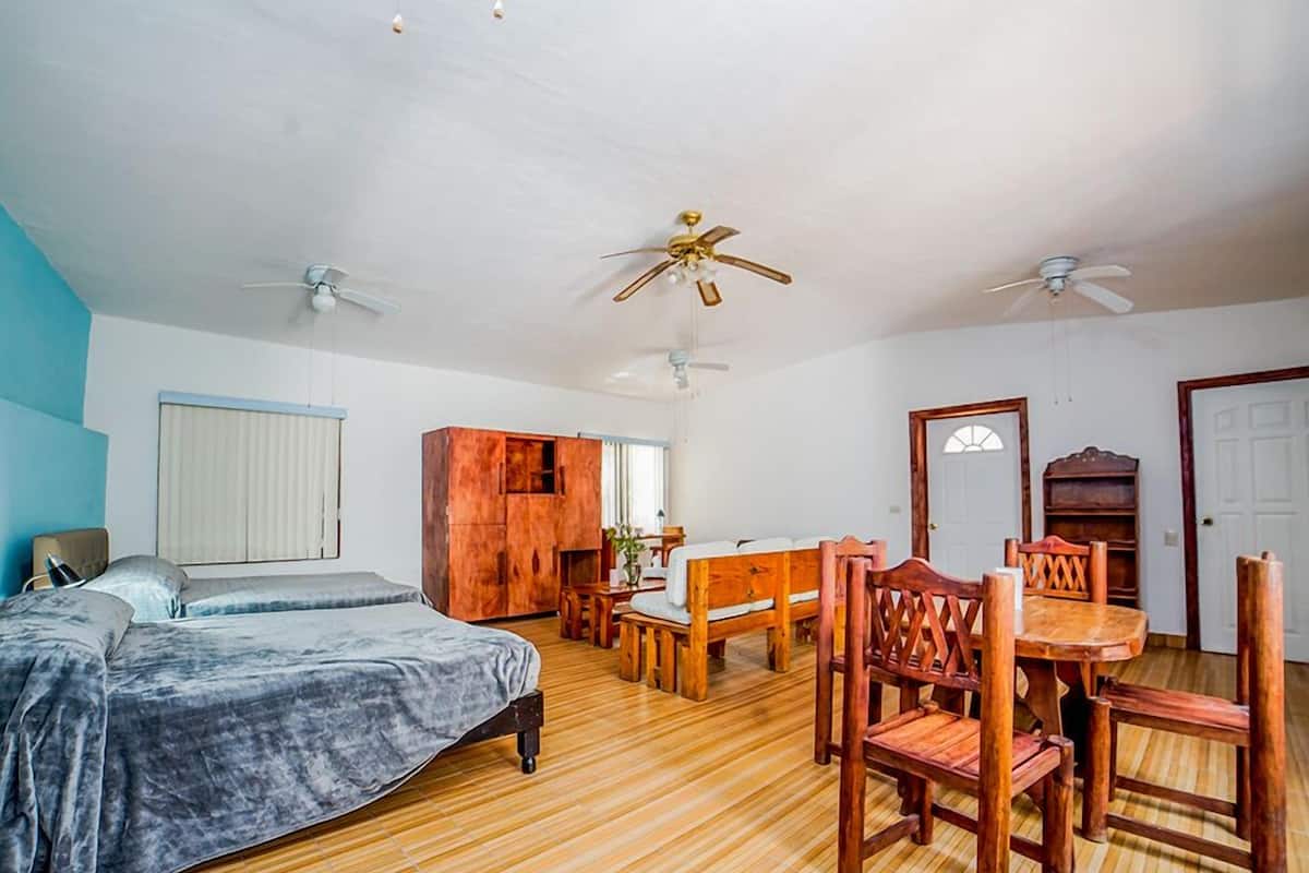 Une chambre à coucher comprenant un lit, une armoire en bois, un bureau avec une chaise et deux ventilateurs de plafond.
