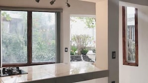 A modern kitchen with a large island, two bar stools, and large windows offering views of the outdoors. - Nido de Colibrí Hotel Relax (Salvatierra)