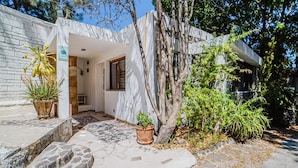 A modern house with a stone pathway leading to the entrance, surrounded by greenery and a tree. - Nido de Colibrí Hotel Relax (Salvatierra)