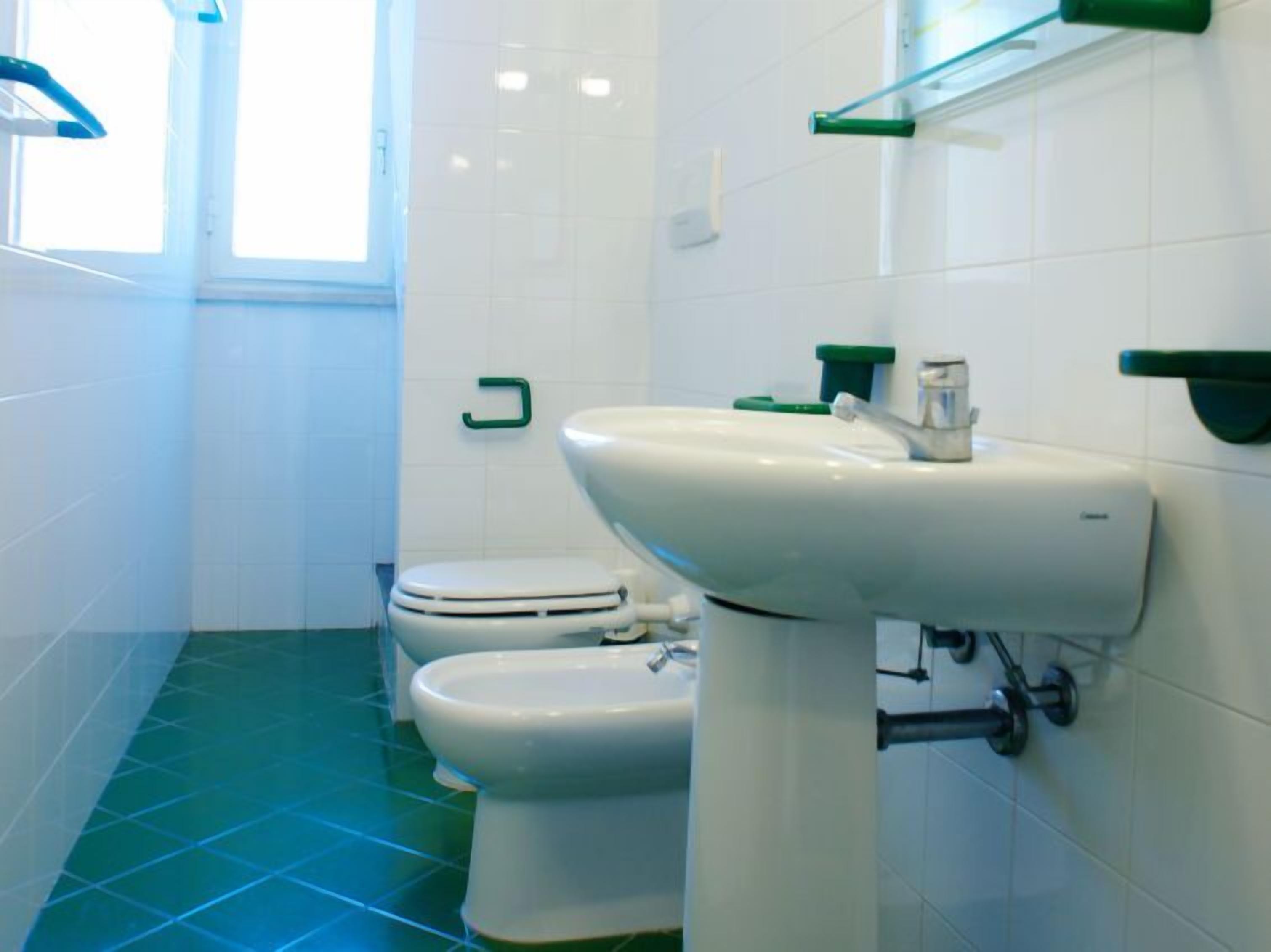 Ein Badezimmer mit Toilette, Bidet und Waschbecken mit Spiegel darüber.