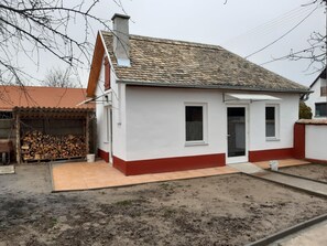 A small, single-story house with a tiled roof, a front door, and a visible chimney.