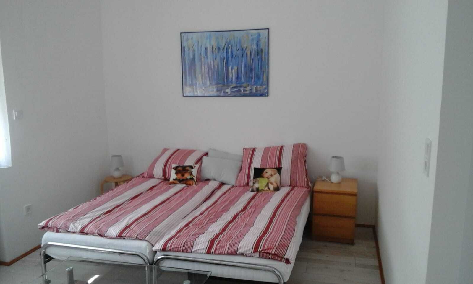 Quarto com duas camas, mesa de cabeceira, luminária e um quadro na parede.