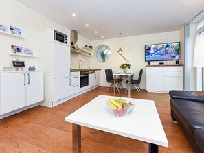 Uma cozinha moderna com armários brancos, micro-ondas e um espaço de refeições com mesa e cadeiras.
