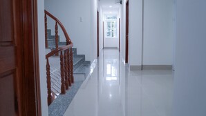 Un pasillo limpio y bien iluminado, con una escalera de madera y un ventanal grande al final.